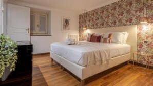 Une chambre à coucher avec un lit, une table de chevet, une lampe fixée au mur et une porte.