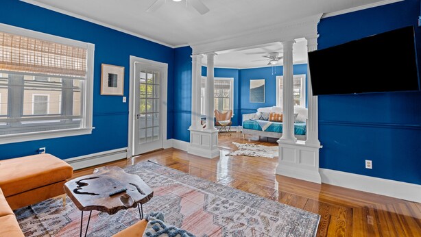 A spacious living room with hardwood floors, a large window, and a ceiling fan. - Updated, Historic District, Walk to Waterfront. Pet-Friendly! Sleeps 12 (Warren)