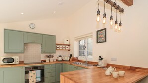 A kitchen with green cabinets, a wooden countertop, a microwave, a kettle, and a coffee maker. - The Nest (Bridgwater)
