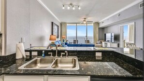 A modern hotel room with a kitchen area, a dining space, and a balcony with a view.