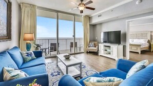 A spacious living area with a balcony, a television, and a comfortable seating arrangement.