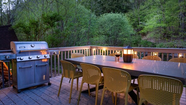 Une terrasse extérieure avec un barbecue, une table et des chaises.