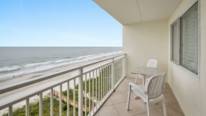Ein Balkon mit Blick auf das Meer, einem Tisch und zwei Stühlen.