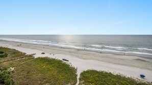 Ein Strand mit einem Holzsteg, sandigem Ufer und dem Meer.