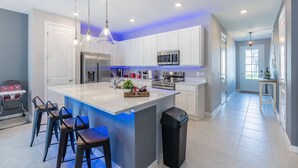 A modern kitchen with a large island, stainless steel appliances, and pendant lighting. - Themed Townhome near Parks and Much More! (Davenport)