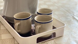 Una tetera blanca con diseños florales y cuatro tazas a juego sobre una bandeja.