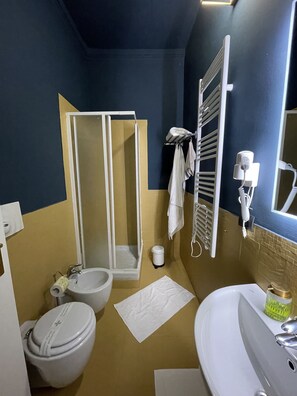 Ein Badezimmer mit Dusche, Toilette, Waschbecken und Handtuchhalter.