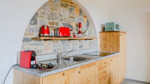 A kitchen with a stone arch, a red coffee maker, a toaster, and a vintage radio.