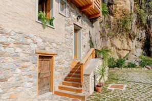 Un bâtiment en pierre avec un escalier en bois menant à une porte.