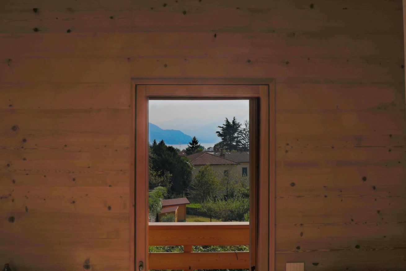 Une porte en bois donnant sur une maison et, au loin, sur des montagnes.