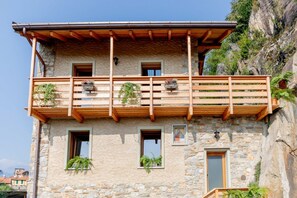 Un bâtiment en pierre doté d’un balcon en bois, de nombreuses fenêtres et de plantes en pot.