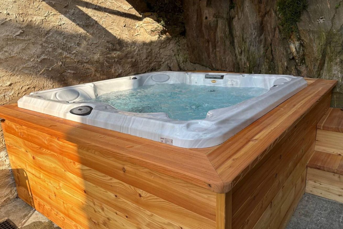 A hot tub with a wooden exterior, set against a natural backdrop.