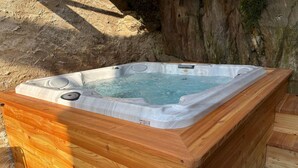 A hot tub with a wooden exterior, set against a natural backdrop. - Green Chalet Scalotta - private Jacuzzi and SPA - few steps from lake and best trekking (Dervio)