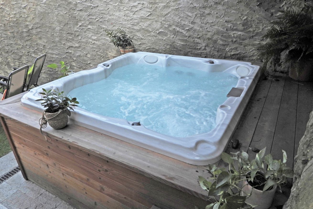 Ein Whirlpool auf einer Holzterrasse mit einer Steinwand im Hintergrund.