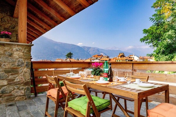 A wooden table set for dining with a stone wall and a view of mountains.