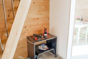 A corner of a room with a wooden wall, a black metal table with a red object on it, and a small shelf with magazines.