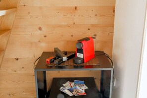 Una mesa pequeña con un dispositivo rojo, un dispositivo negro y algunos documentos.
