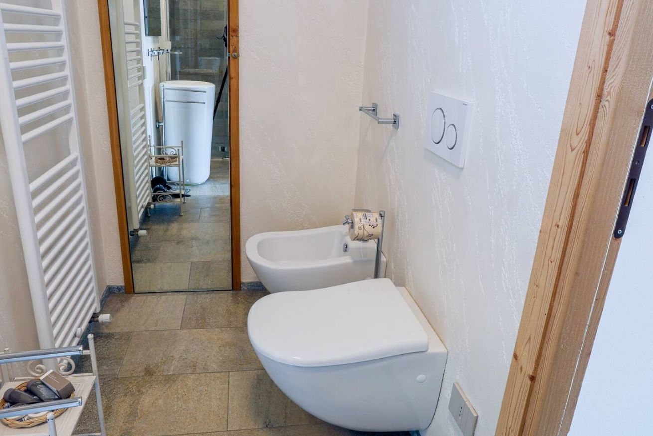 A bathroom with a toilet, bidet, and a towel rack.