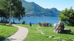 A park with a paved path, benches, picnic tables, and a large rock. - Green Chalet Scalotta - private Jacuzzi and SPA - few steps from lake and best trekking (Dervio)