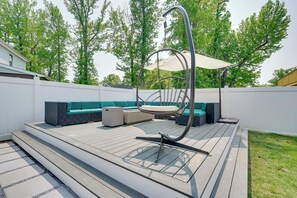 Une terrasse en bois avec un canapé et un fauteuil suspendu.