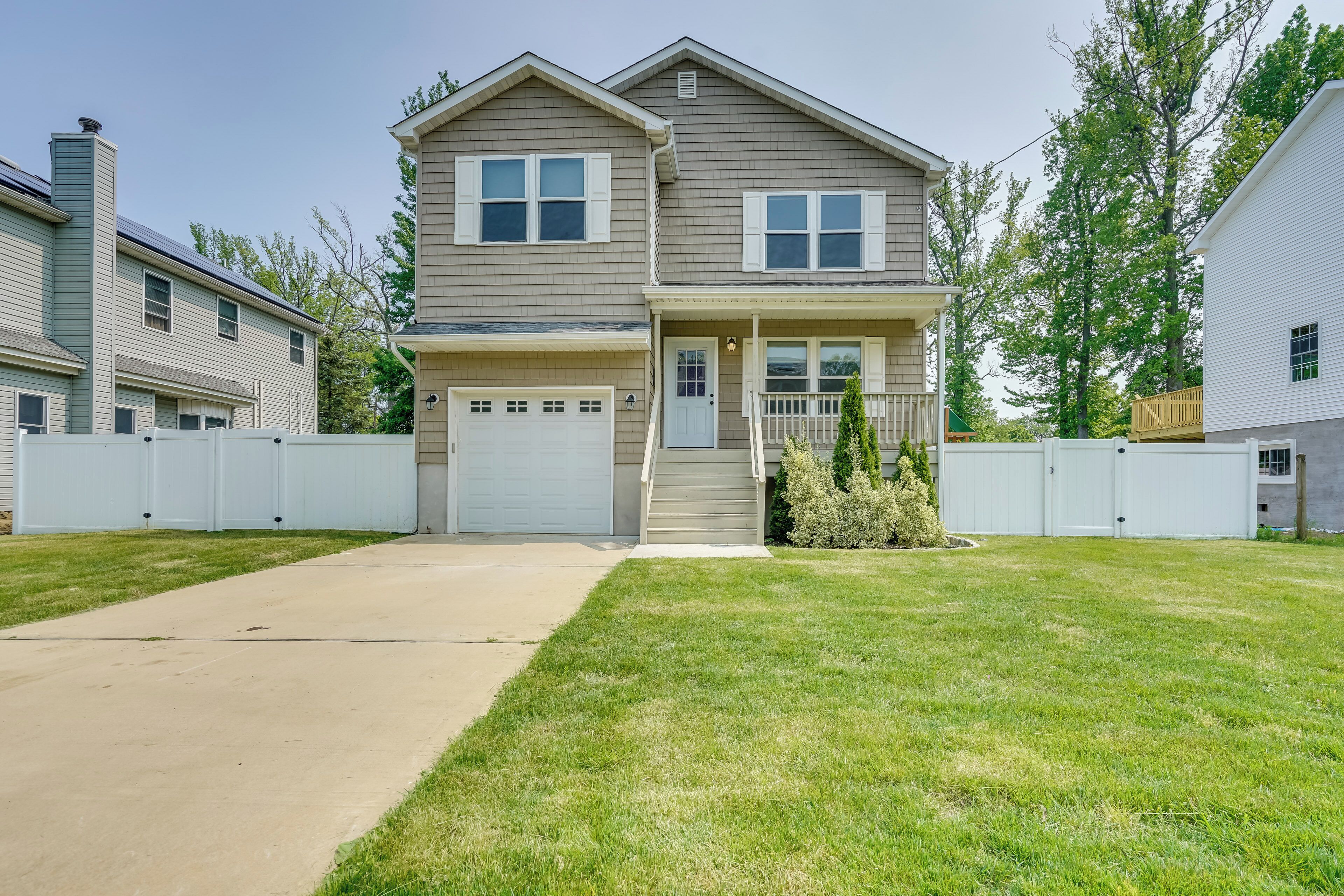 A two-story house with a front garage, a covered porch, and a well-maintained lawn.