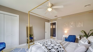 Une chambre à coucher avec un lit à baldaquin, un ventilateur de plafond, un bureau avec une chaise et un miroir.