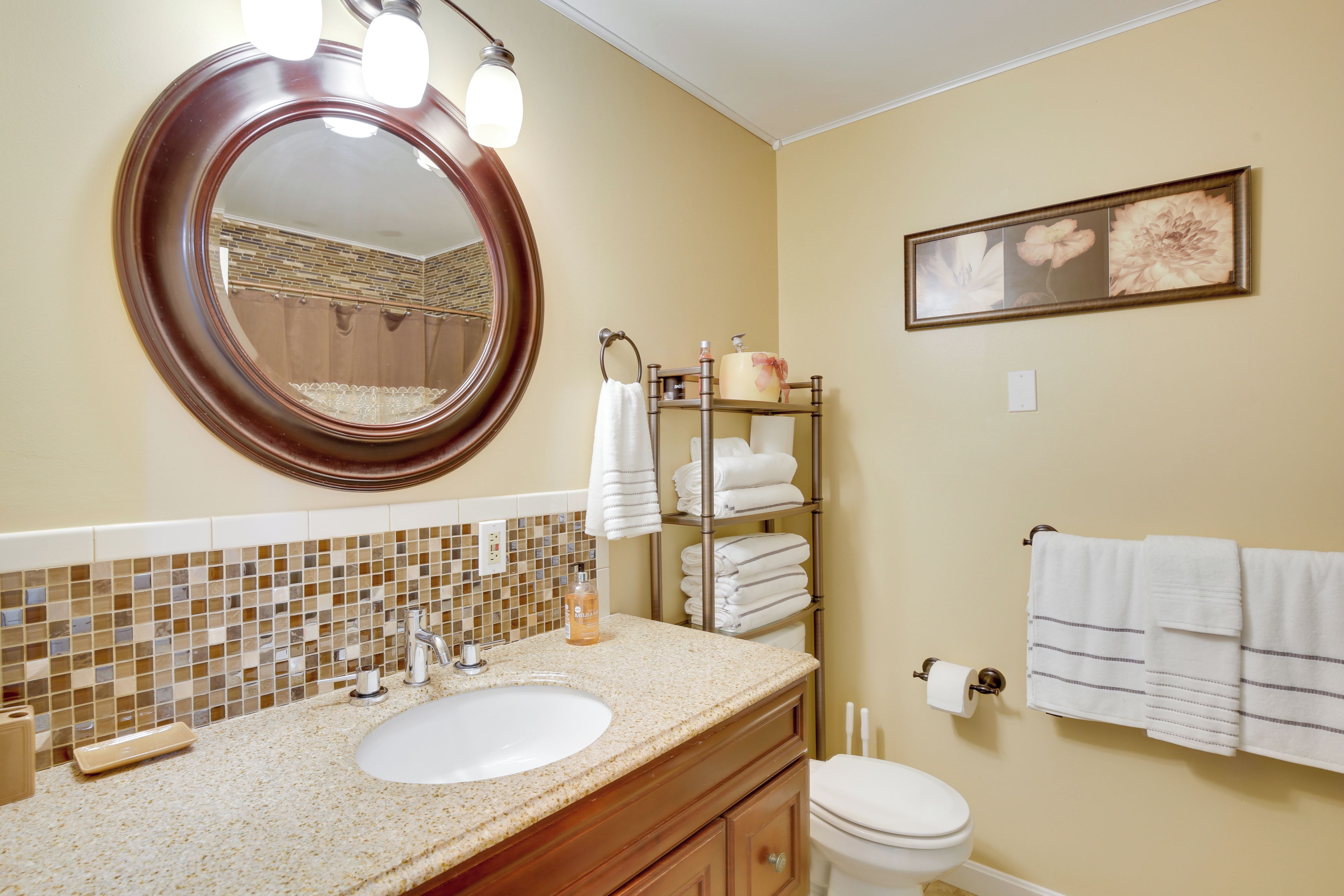 A bathroom with a round mirror, a sink, a toilet, and a towel rack.