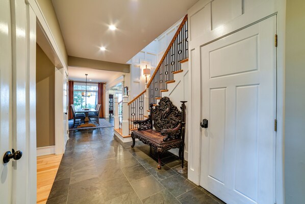 A hallway with a wooden floor, a white door, and a staircase with a wooden railing. - Secluded Ithaca Home w/ Hot Tub ~ 5 Mi to Cornell! (Ithaca)