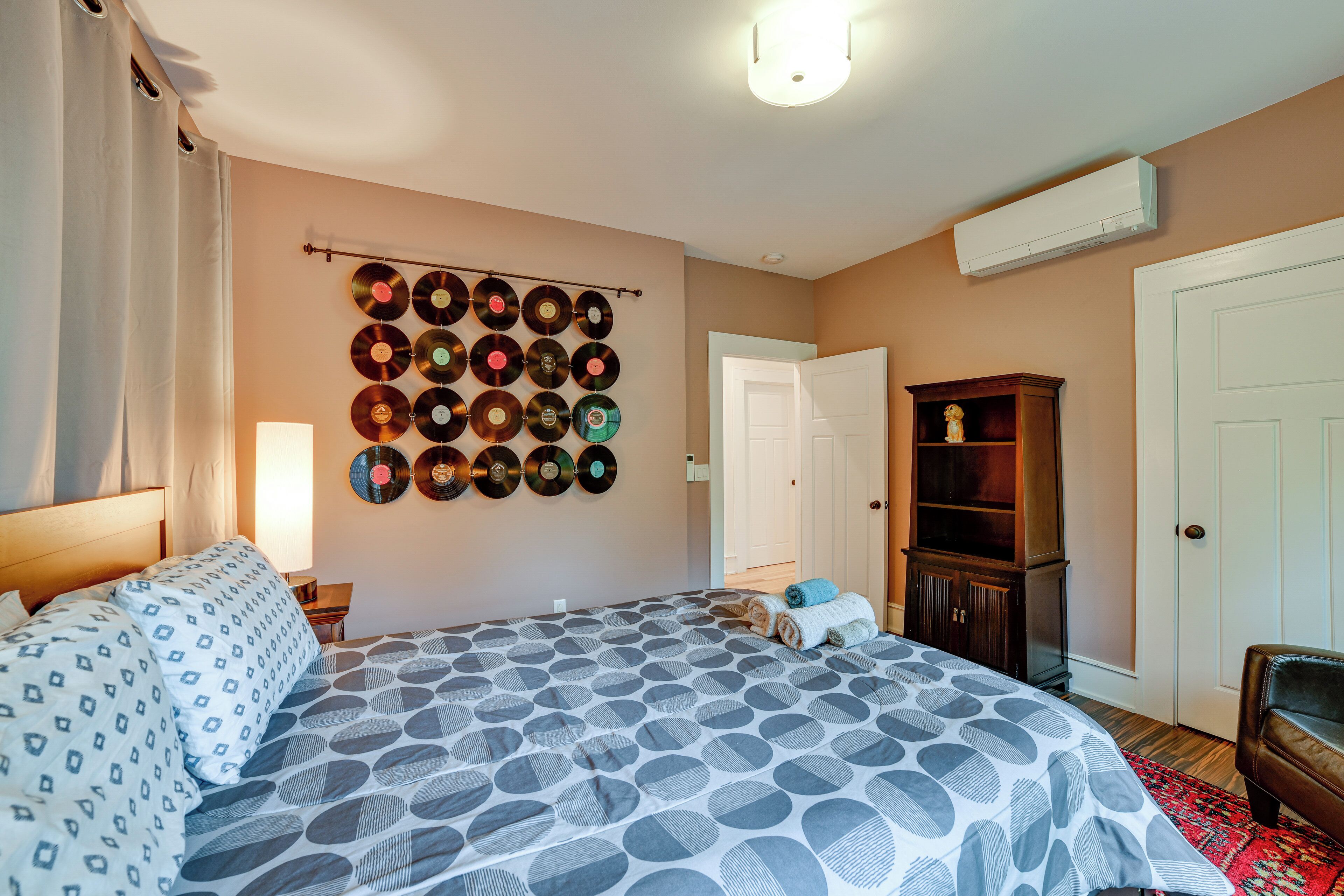 Un dormitorio con cama, estantería de discos en la pared, armario y mesita de noche.