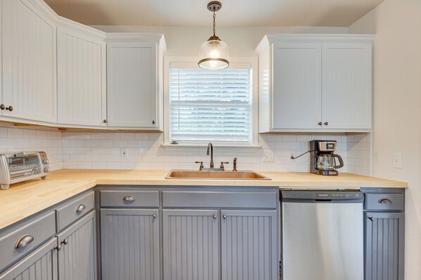 A kitchen with white cabinets, a dishwasher, a coffee maker, and a toaster on the countertop. - Updated Home w/ Yard ~ 14 Mi to Quartz Mountain! (Mangum)