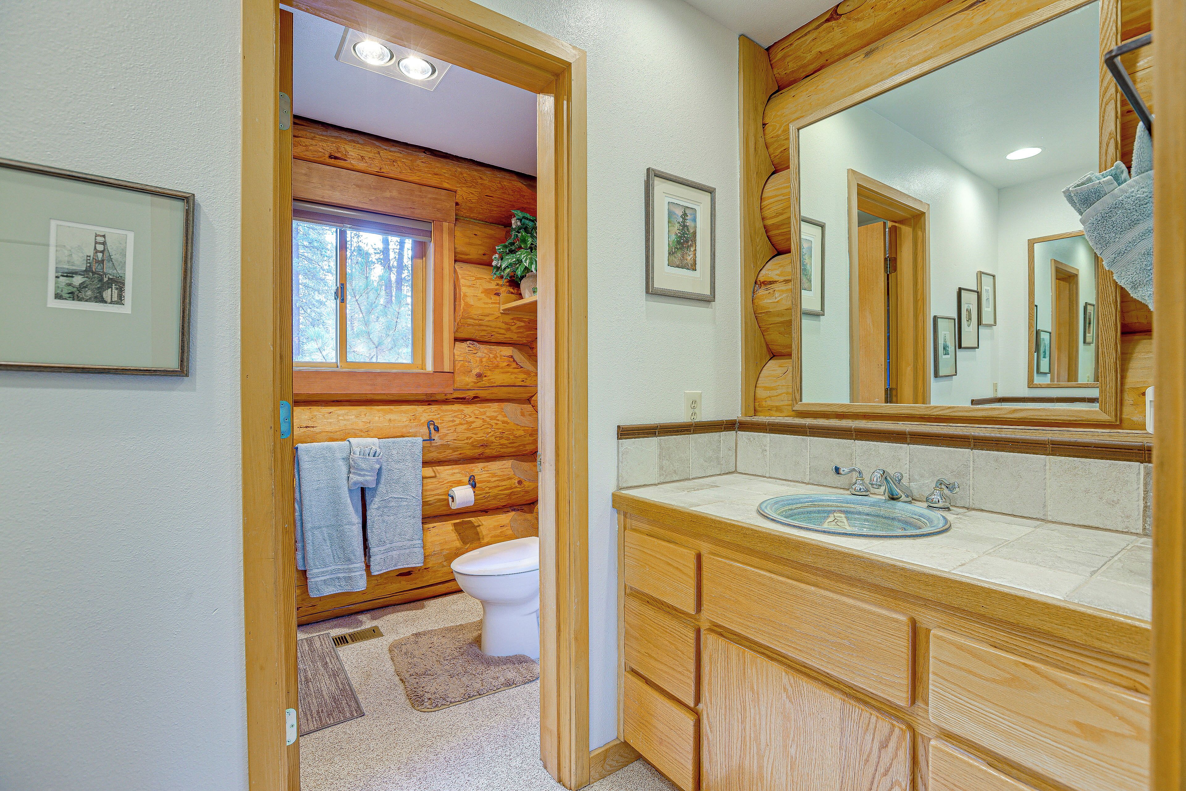 Un baño de cabaña de madera con un espejo grande, armarios de madera y un lavabo.