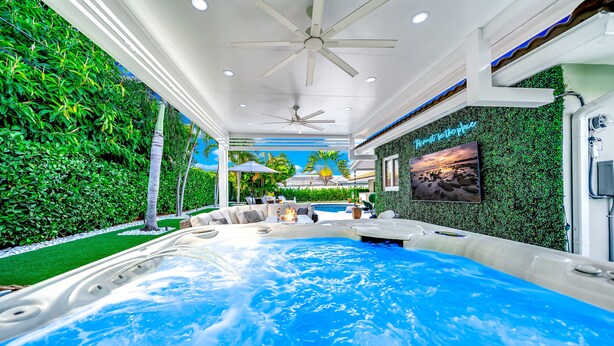 A hot tub area with a ceiling fan, a pool, and a wall with a green leafy pattern. - Heated SaltWater Pool+HotTub! Golf Cart+1 Mile To Beach! (Fort Lauderdale)