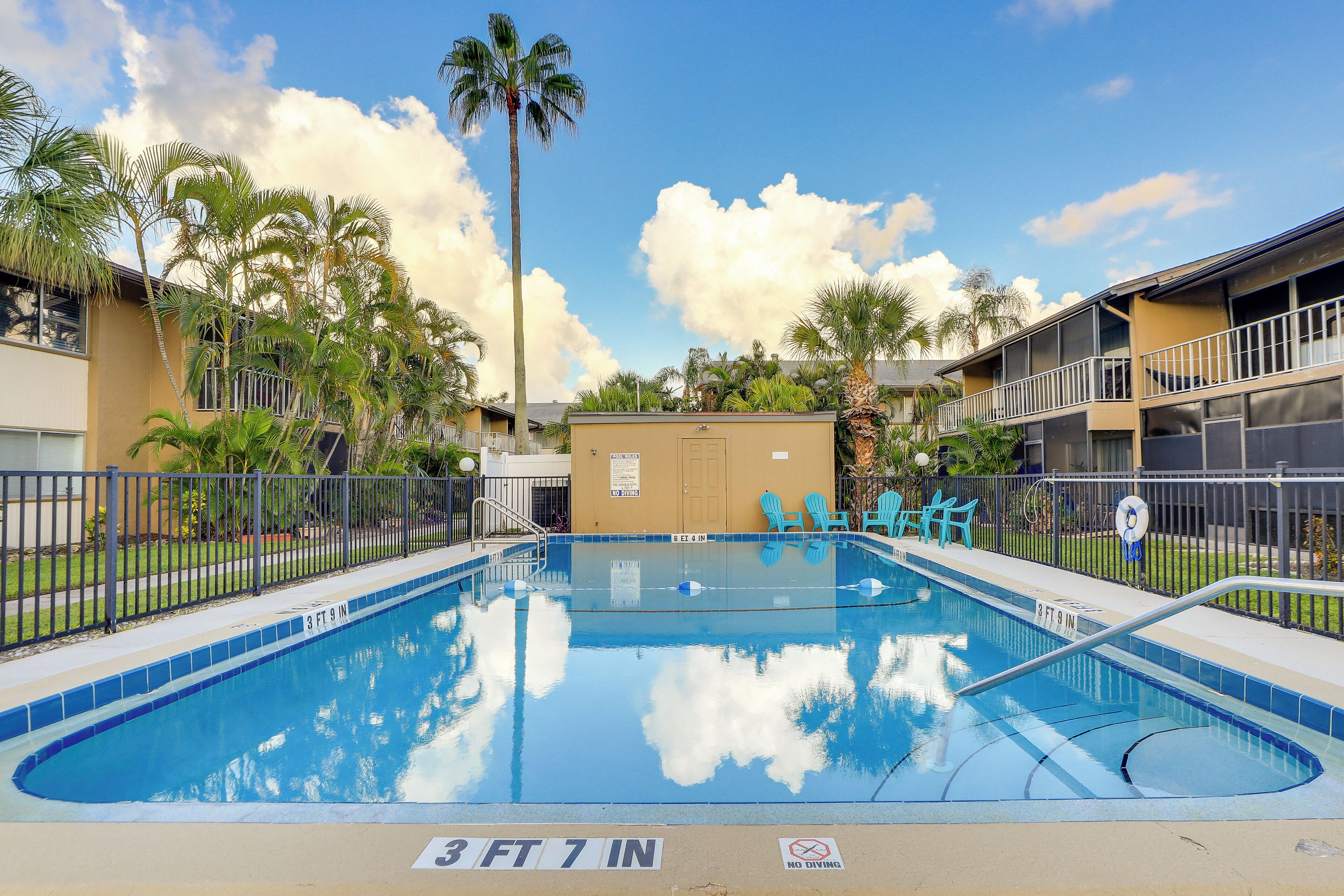 A swimming pool with a 3 ft 7 in depth, surrounded by palm trees and a fence.