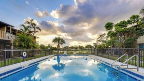 A swimming pool with a clear blue water surface, surrounded by a metal fence and palm trees. - Welcoming Sarasota Vacation Rental w/ Pool! (Sarasota)