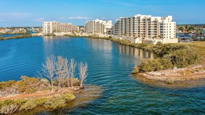 A waterfront hotel with multiple buildings, a clear blue sky, and calm water. - Gulf-view Balcony & Pool Access: Hudson Retreat (Hudson)