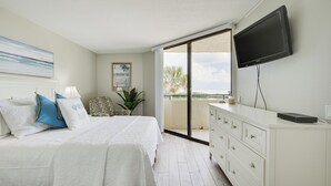 A bedroom with a bed, a TV, a dresser, and a balcony with a view. - Gulf-view Balcony & Pool Access: Hudson Retreat (Hudson)
