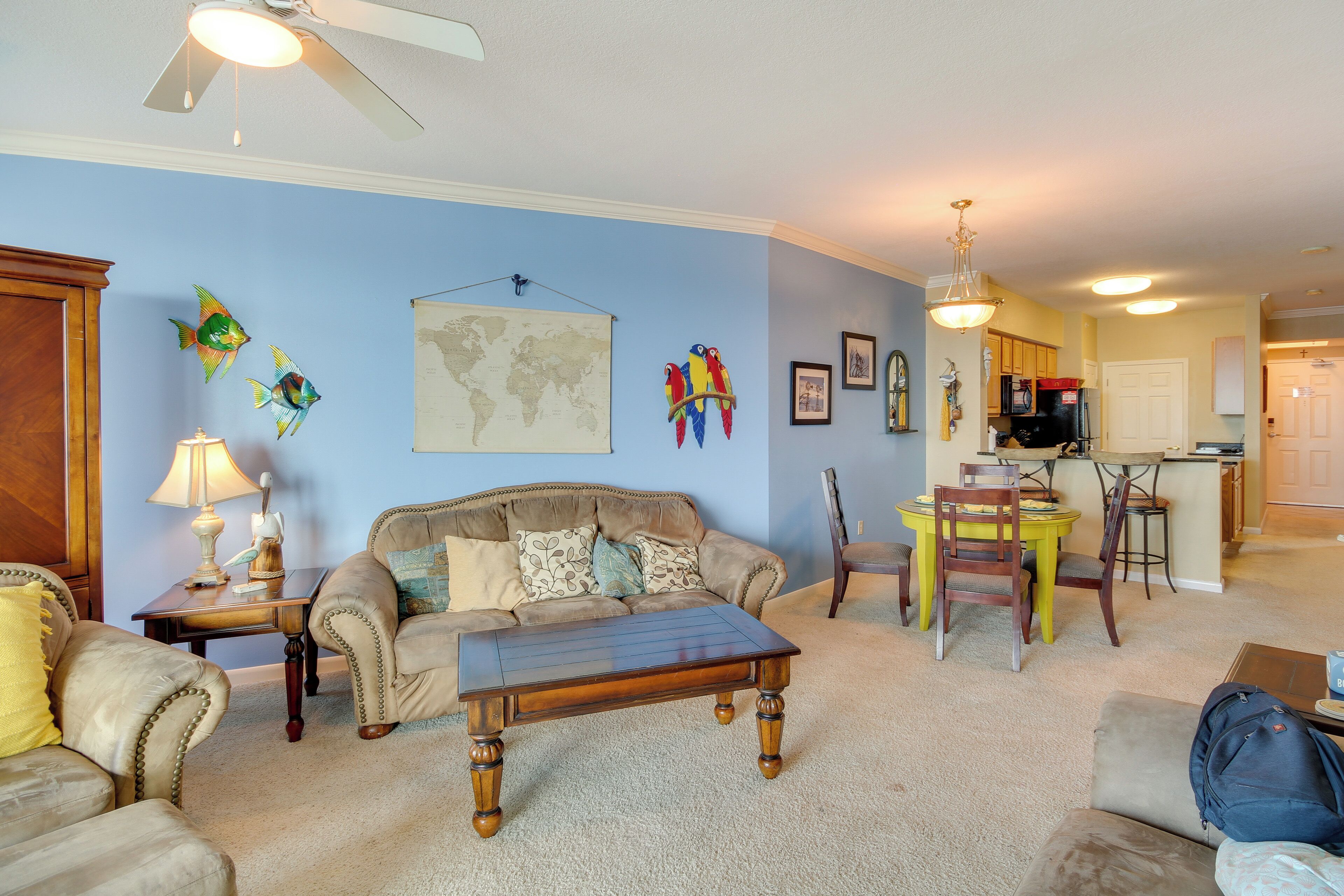 A living room with a brown sofa, a wooden coffee table, and a dining area with a yellow table and chairs.