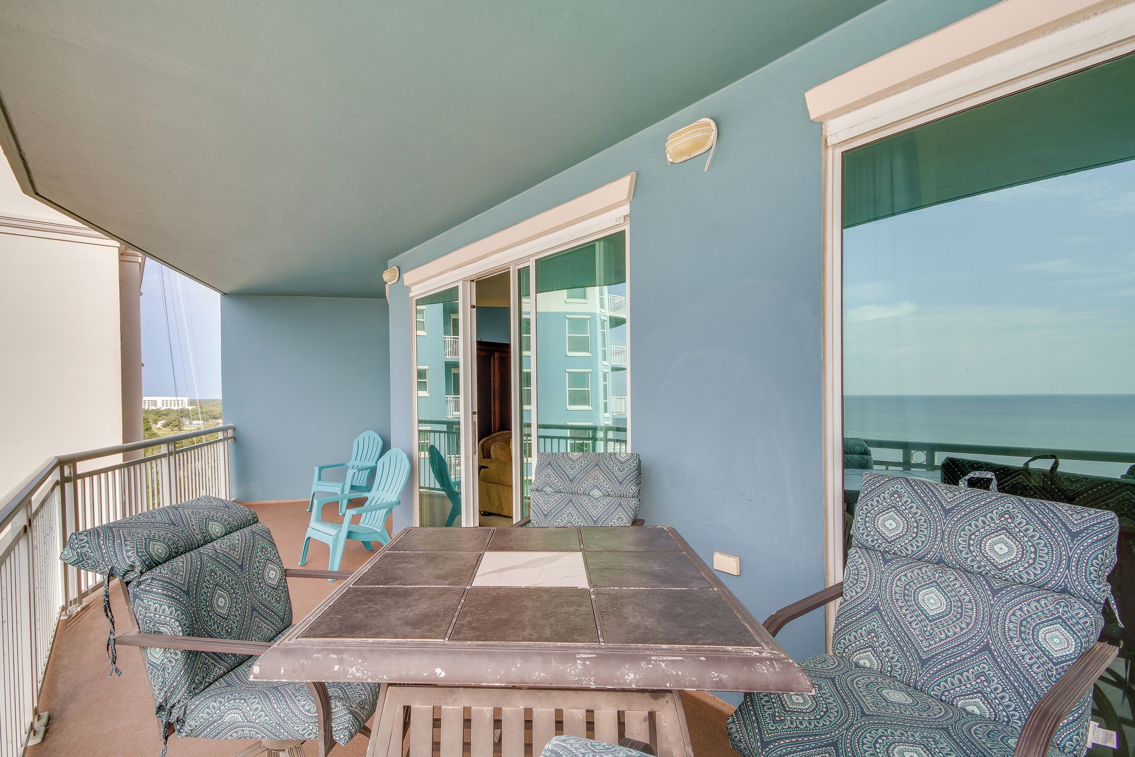 A balcony with a table and chairs, a view of the ocean, and a door leading to an interior space.