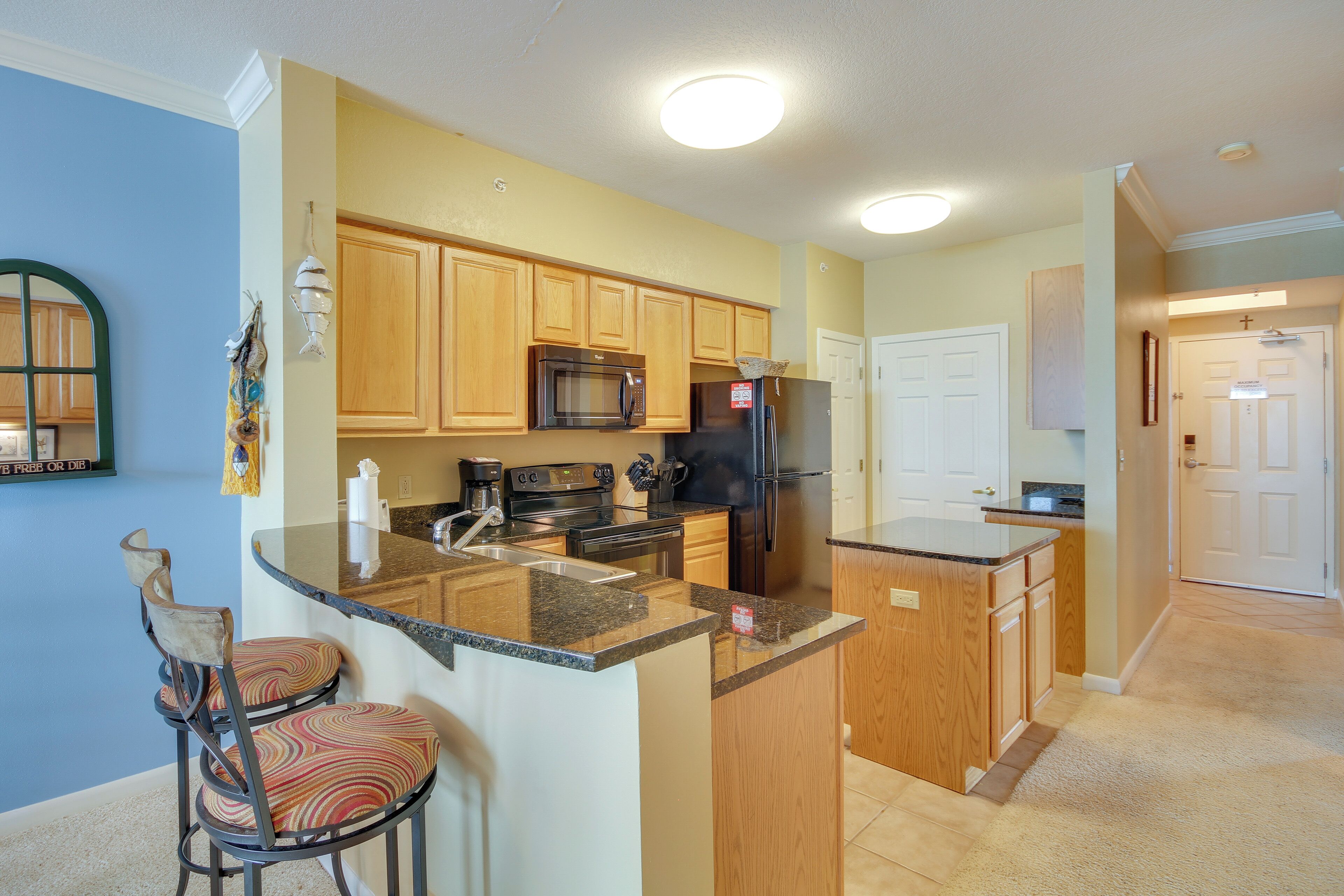A kitchen with wooden cabinets, a microwave, a refrigerator, and a sink.