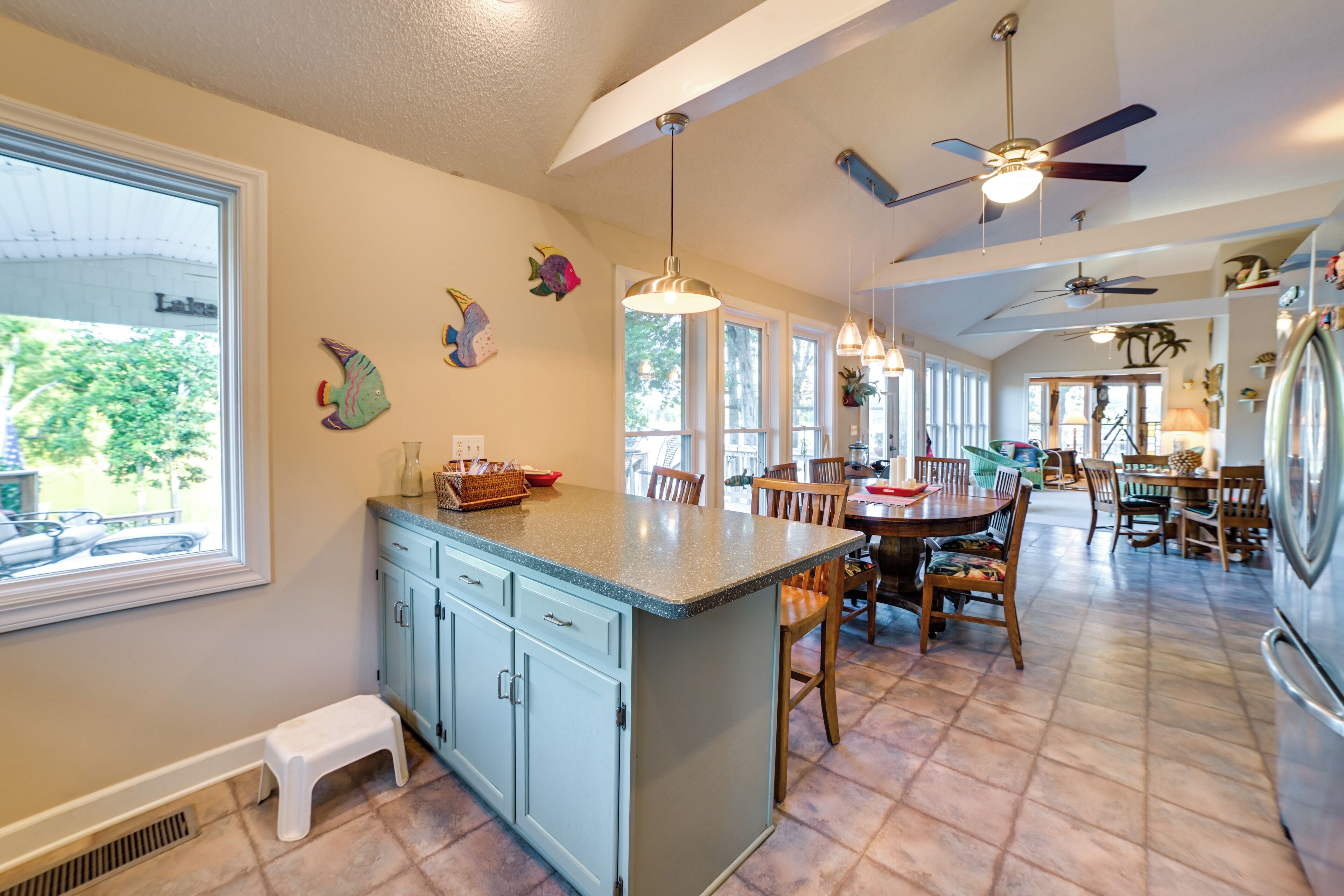 A kitchen with a central island, wooden chairs, and a dining table.