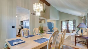 A dining area with a long table, chairs, and a chandelier. There is a piano in the background and a door with a blue frame. - Spacious Aurora Retreat w/ Game Room + Hot Tub! (Aurora)