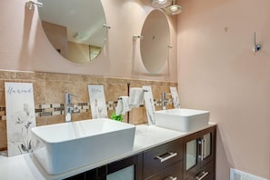 Une salle de bain moderne avec deux vasques, un miroir au-dessus de chacune, et un mur recouvert de carreaux décoratifs.