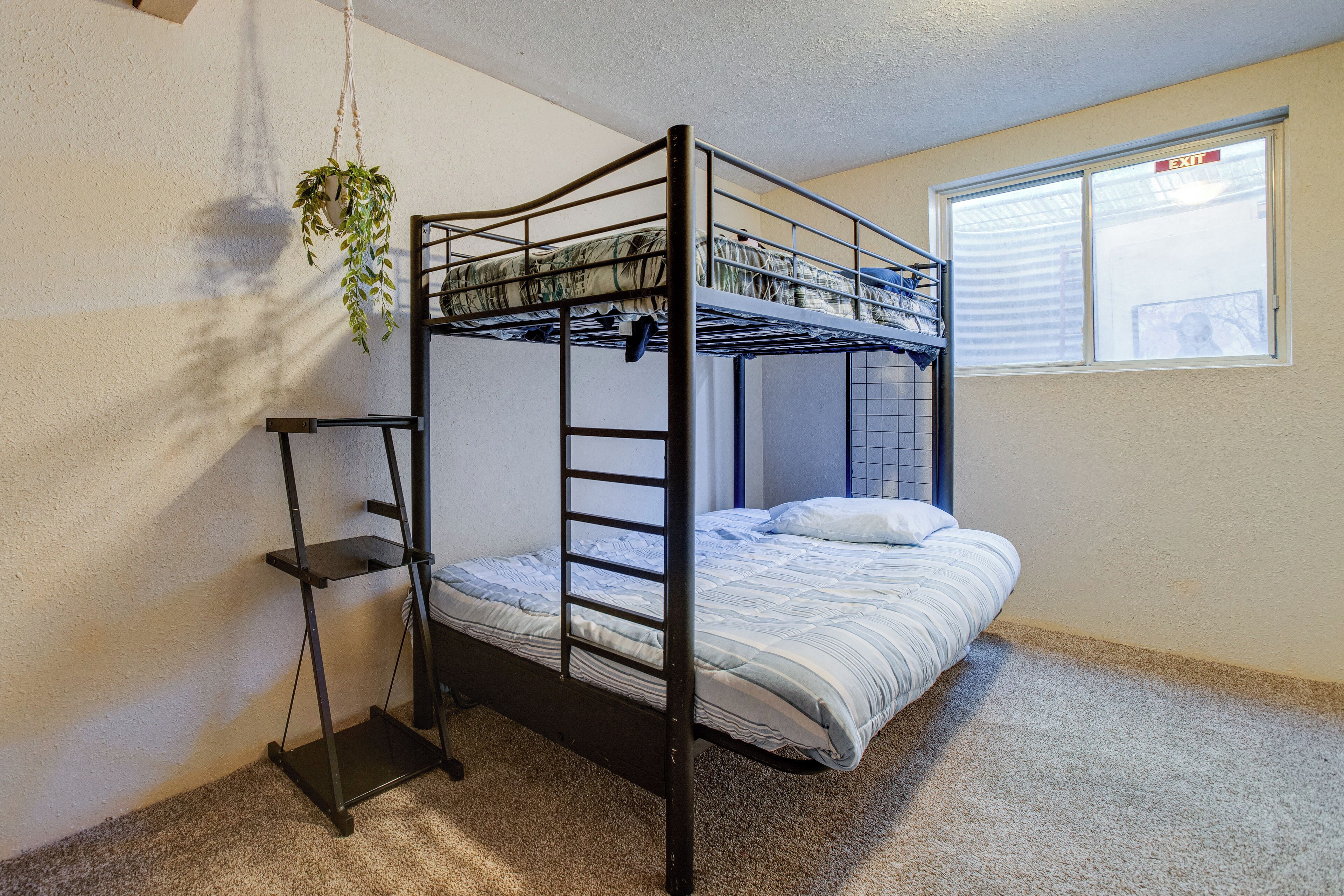 A bunk bed with a metal frame, a shelf, and a hanging plant.