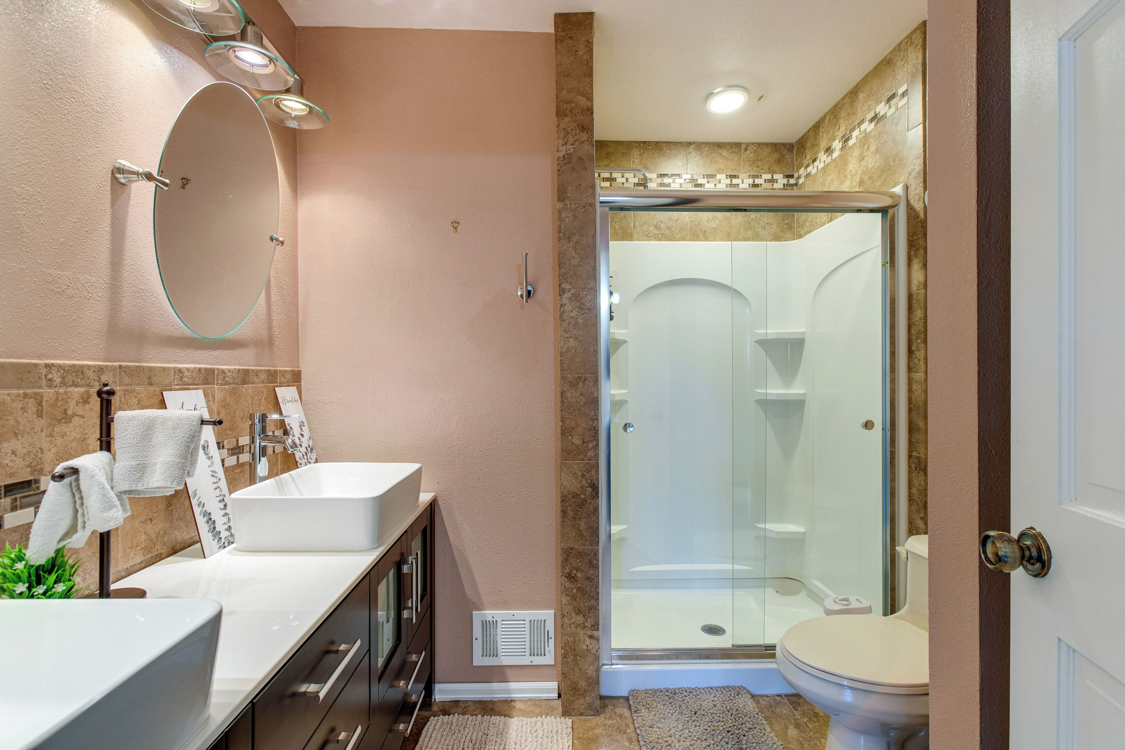 A bathroom with a glass-enclosed shower, a white sink, and a large mirror.