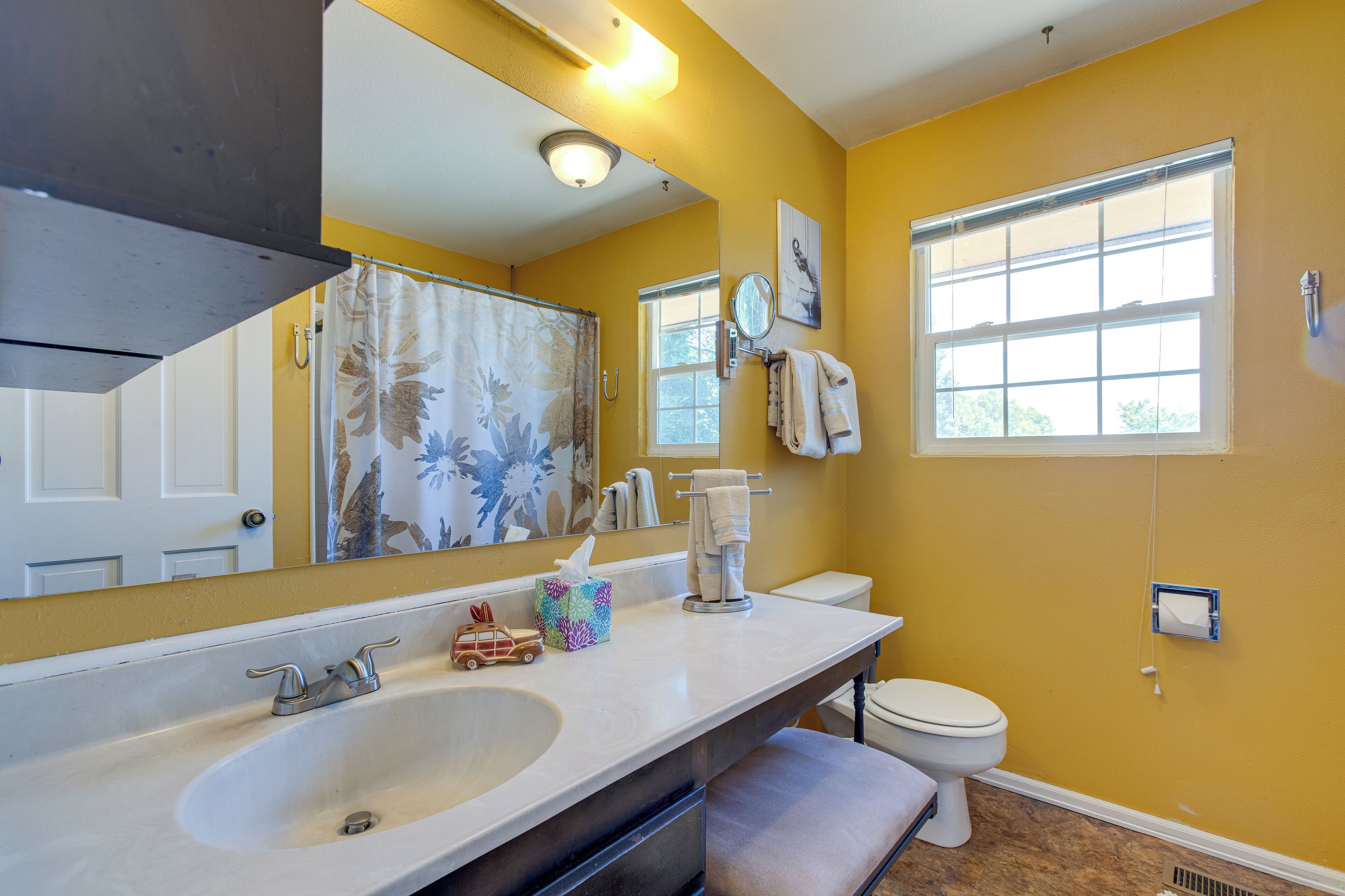 A bathroom with a large sink, toilet, and a window.