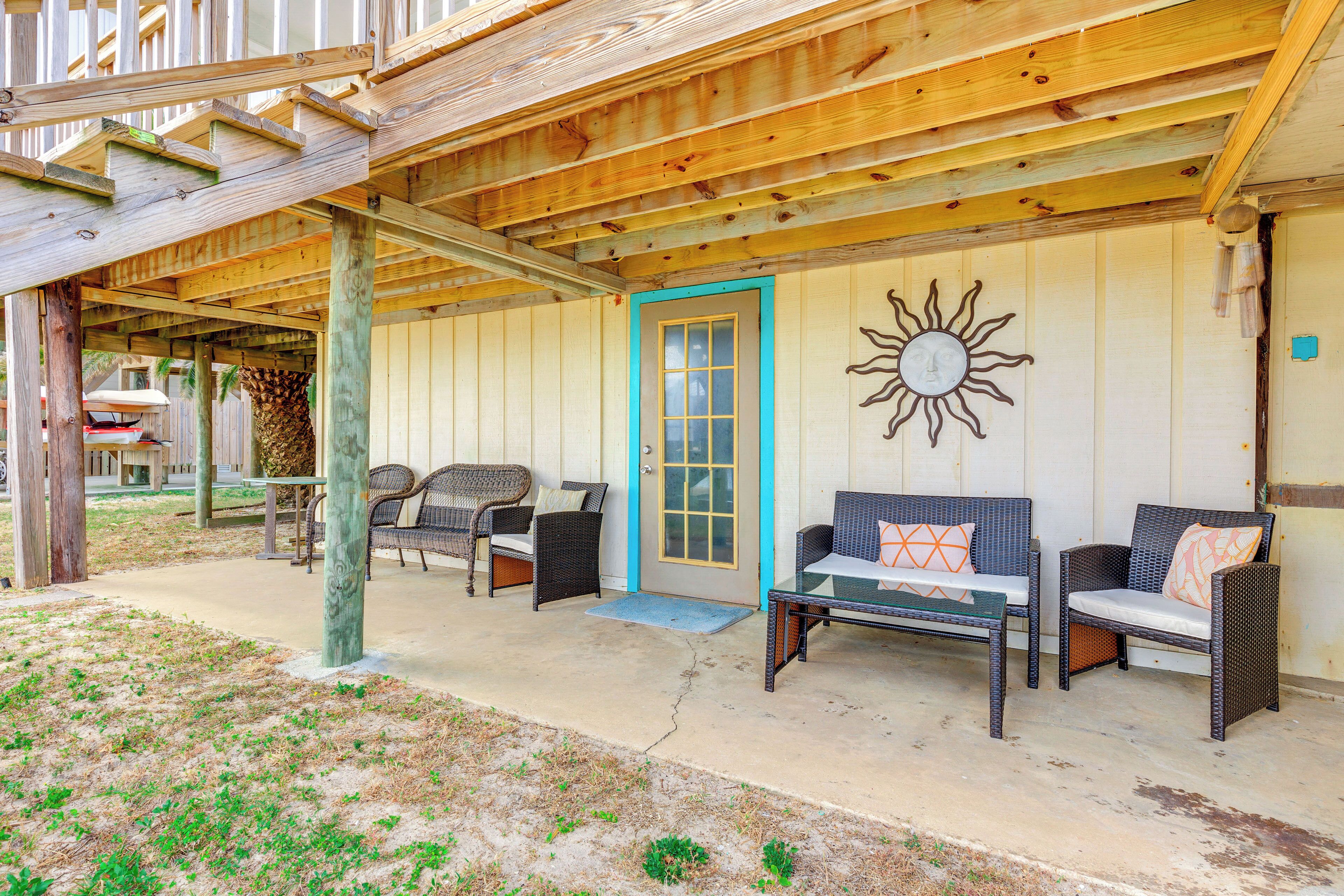 A covered outdoor seating area with wicker furniture and a sun decoration.