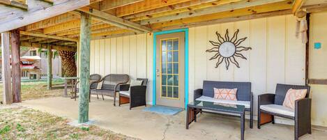 A covered outdoor seating area with wicker furniture and a sun decoration.