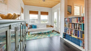 Una habitación con un sofá blanco, una estantería y un ventilador de techo de madera.