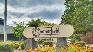 A sign for Summerfield Clubhouse surrounded by well-maintained gardens and trees. - Portland Area Retreat in North Wine Country! (Tualatin)