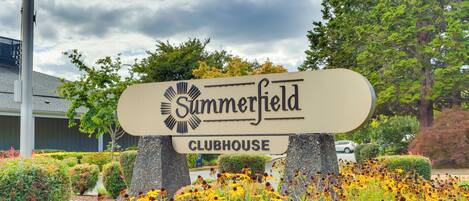 A sign for Summerfield Clubhouse surrounded by well-maintained gardens and trees.